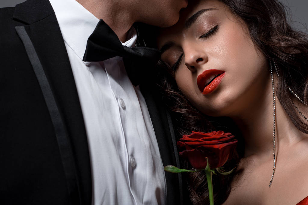όμορφο ρομαντικό ζευγάρι αγκαλιάζει και κρατώντας κόκκινο τριαντάφυλλο λουλούδι  - Φωτογραφία, εικόνα