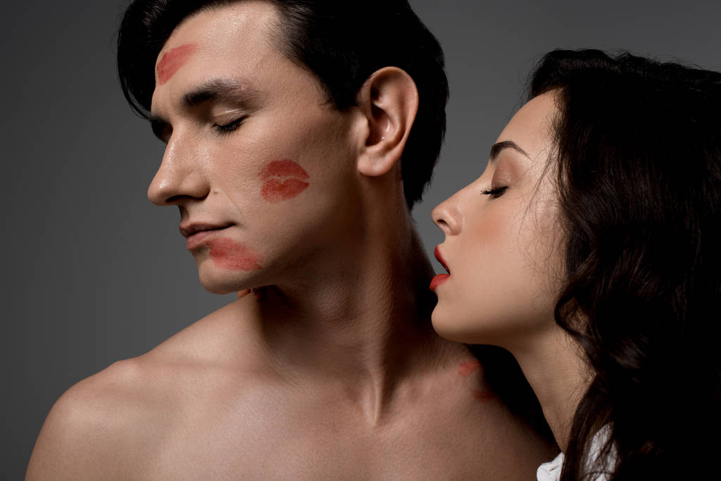 sensuele vrouw en man met rode lippenstift afdrukken, geïsoleerd op grijs - Foto, afbeelding