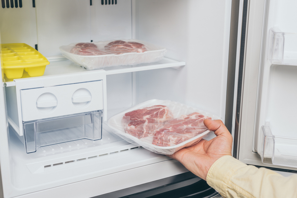 vista ritagliata dell'uomo che estrae carne congelata dal congelatore
 - Foto, immagini