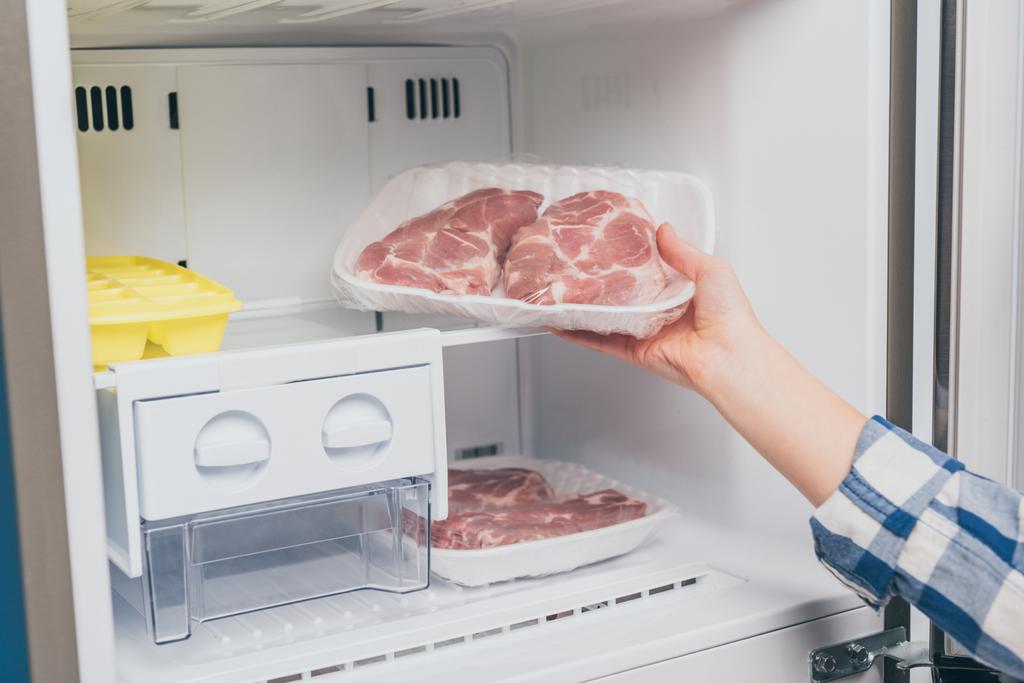vista recortada de la mujer sacando carne congelada del congelador
 - Foto, imagen