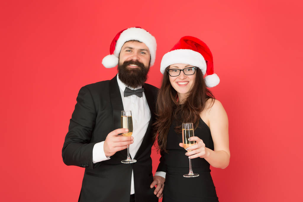 Čas na vánoční večírek. formální zamilovaný pár slaví nový rok. Muž ve smokingu se ženou v Santově klobouku. Veselé Vánoce a veselé Vánoce všem. obchodník a dívka pijí šampaňské. Vánoční večírek - Fotografie, Obrázek