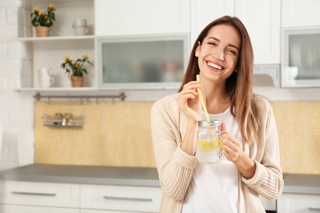 Mujer joven con tarro de masón de agua de limón en la cocina
 - Foto, Imagen