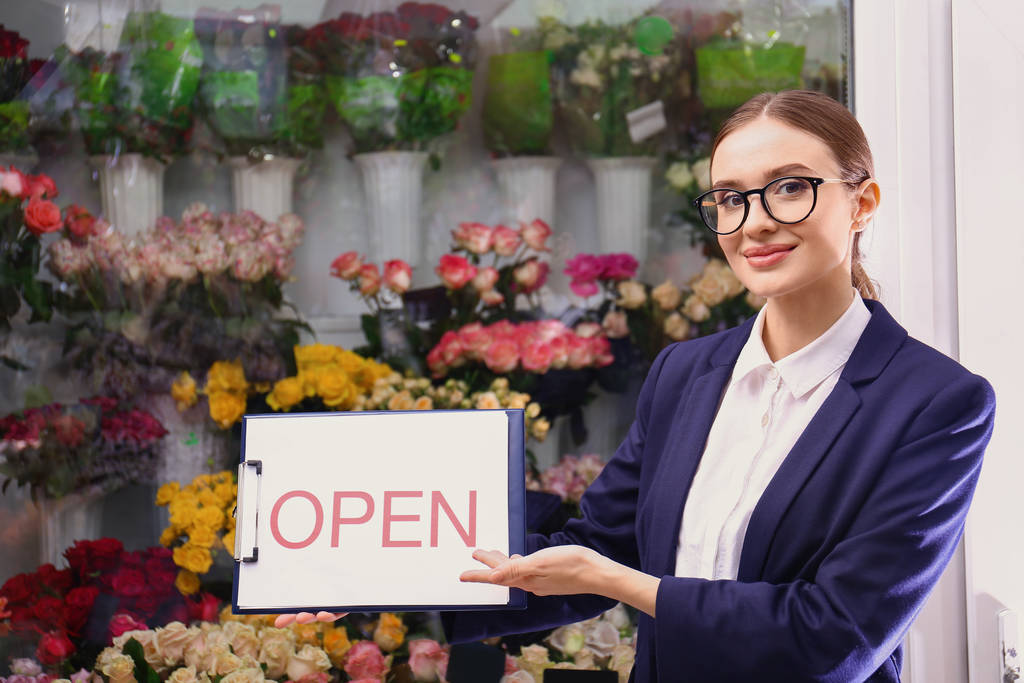 Владелец женского бизнеса держит табличку OPEN возле цветочного магазина
 - Фото, изображение