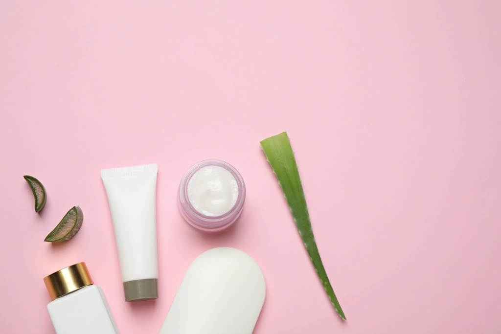 Composición plana con aloe vera y productos cosméticos sobre fondo rosa. Espacio para texto
 - Foto, imagen