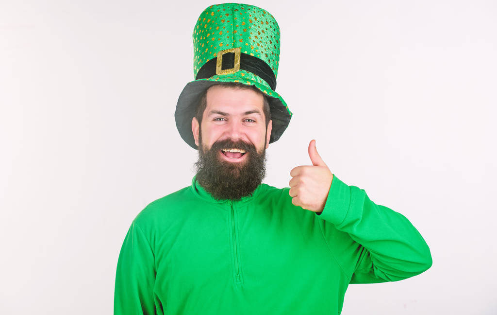 Przedstawienie jego kciuki w górze. Szczęśliwy człowiek irlandzki z brodą, ubrany w zielony. Hipster w leprechaun kapelusz i strój. Brodaty mężczyzna obchodzi Dzień Świętego patricks. Happy saint Patryka - Zdjęcie, obraz