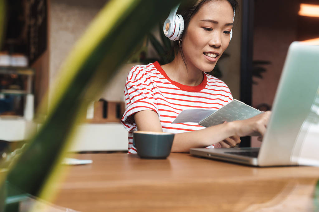 Portret radosnej azjatki ze słuchawkami za pomocą laptopa w c - Zdjęcie, obraz