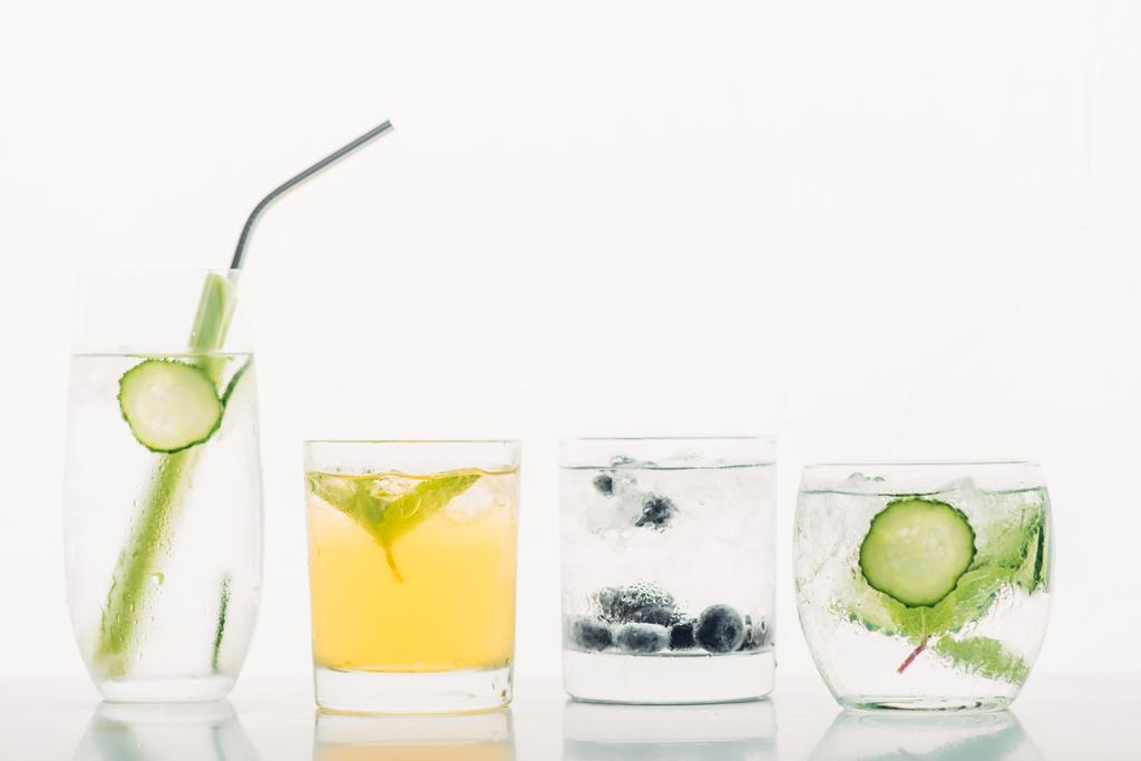 bebidas refrescantes com mirtilos, aipo, palha, hortelã, pepino e gelo isolados em branco
 - Foto, Imagem