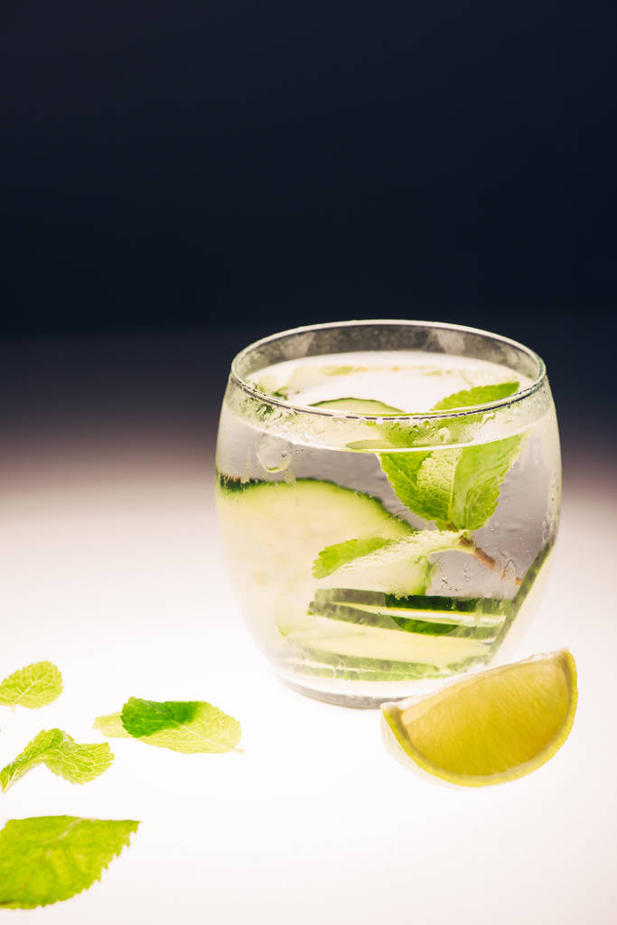 refreshing lemonade with mint, cucumber and lime on illuminated surface on black background - Photo, Image