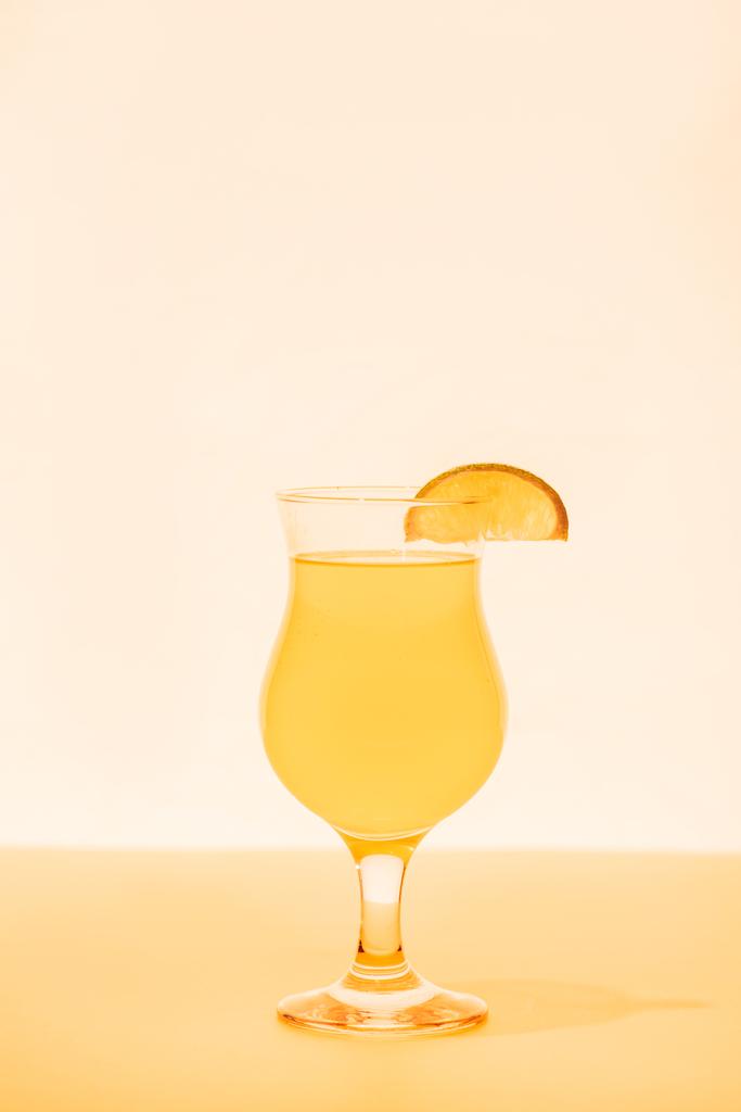 cóctel amarillo con rodajas de cítricos sobre fondo brillante
 - Foto, Imagen