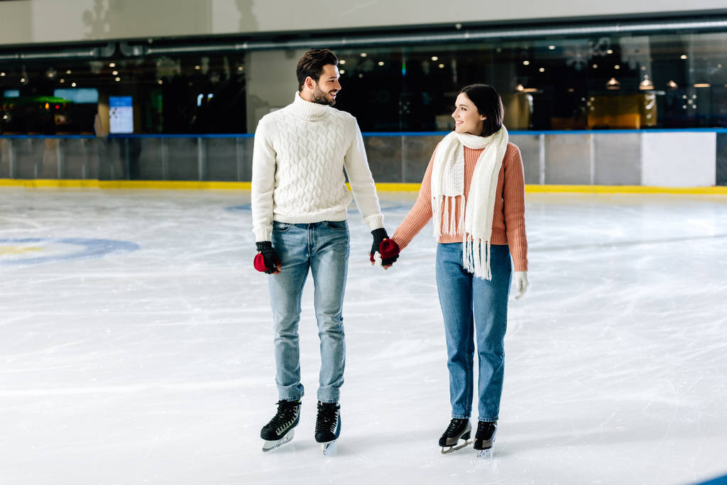 gyönyörű boldog pár fogja egymás kezét a korcsolyapályán  - Fotó, kép
