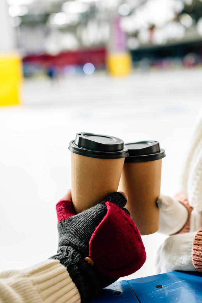 przycięty widok na parę gospodarstwa jednorazowych filiżanek kawy iść na lodowisko - Zdjęcie, obraz