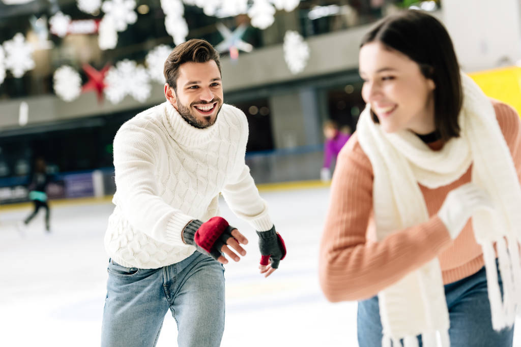 enfoque selectivo de alegre pareja joven divirtiéndose mientras patina en la pista de patinaje
   - Foto, imagen