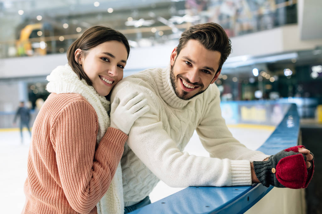 νεαρό θετικό ζευγάρι σε πουλόβερ που ξοδεύει χρόνο σε παγοδρόμιο   - Φωτογραφία, εικόνα