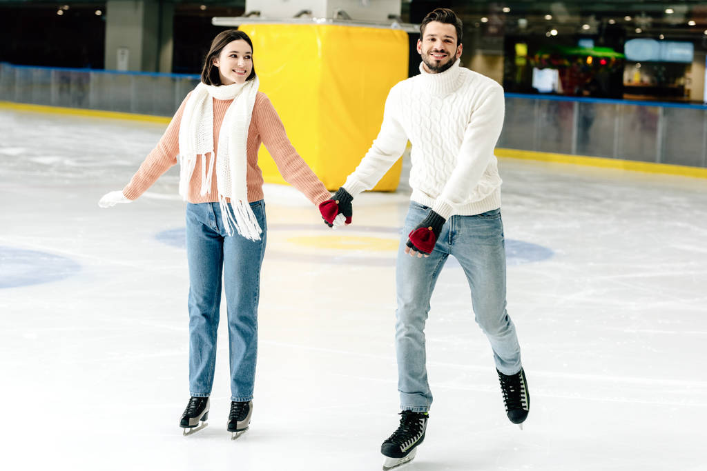 νεαρό ζευγάρι που κρατιέται χέρι-χέρι και περνάει χρόνο στο παγοδρόμιο   - Φωτογραφία, εικόνα