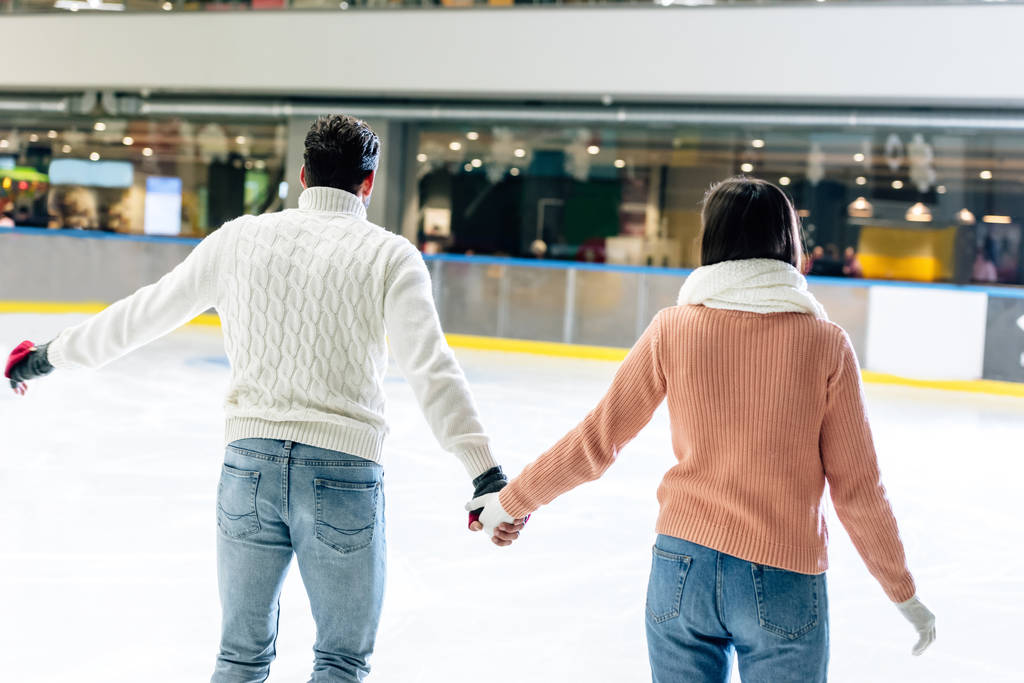 vue arrière du jeune couple tenant la main sur la patinoire
  - Photo, image