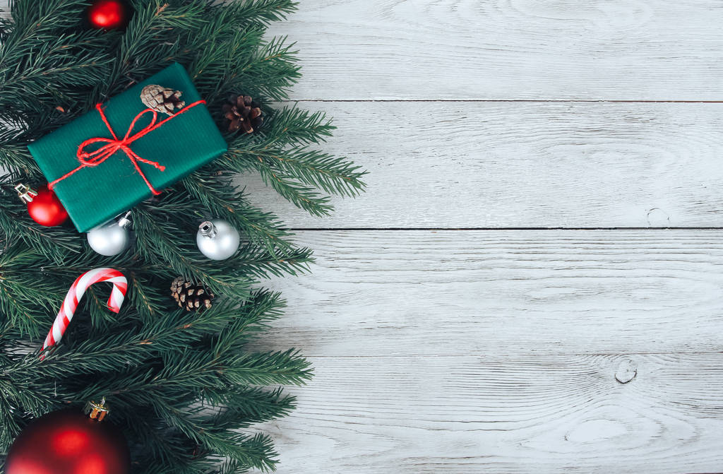 Красные и серебряные рождественские безделушки, елки, подарки, леденцы на белом деревянном столе. Рождественский фон Новый год, зимние каникулы, копировальное пространство, вид сверху
 - Фото, изображение