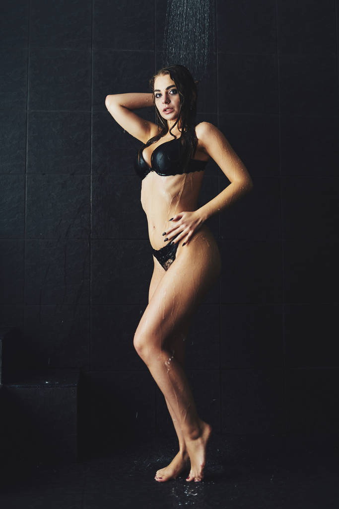 A beautiful girl is standing in the shower. Wet photo shoot - Photo, Image