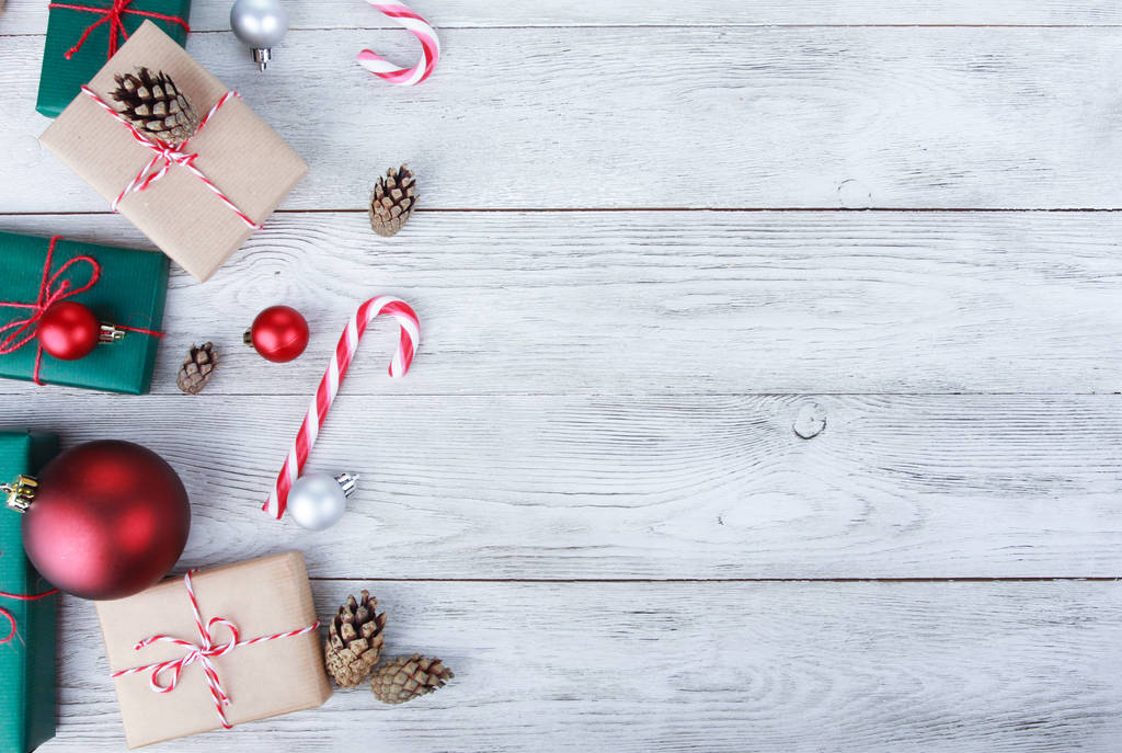 Bolas de Navidad, regalos, bastones de caramelo, conos de abeto en la mesa de madera blanca. Concepto de fondo de Navidad. Año Nuevo, vacaciones de invierno, espacio para copiar, vista superior
 - Foto, imagen