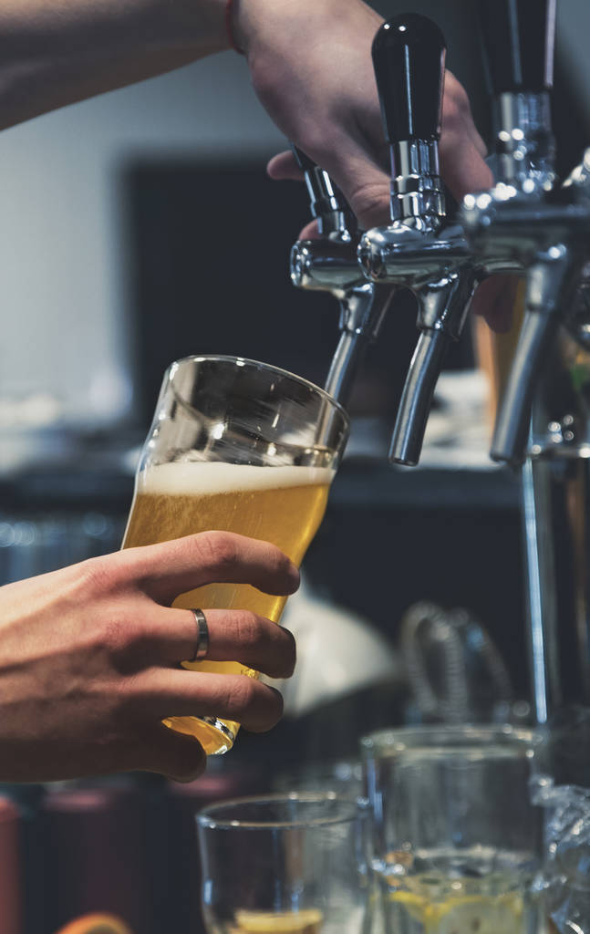μπάρμαν χέρι σε βρύση μπύρα ρίχνει μια βαρελίσια μπύρα σε ποτήρι που σερβίρεται σε ένα εστιατόριο ή παμπ - Φωτογραφία, εικόνα