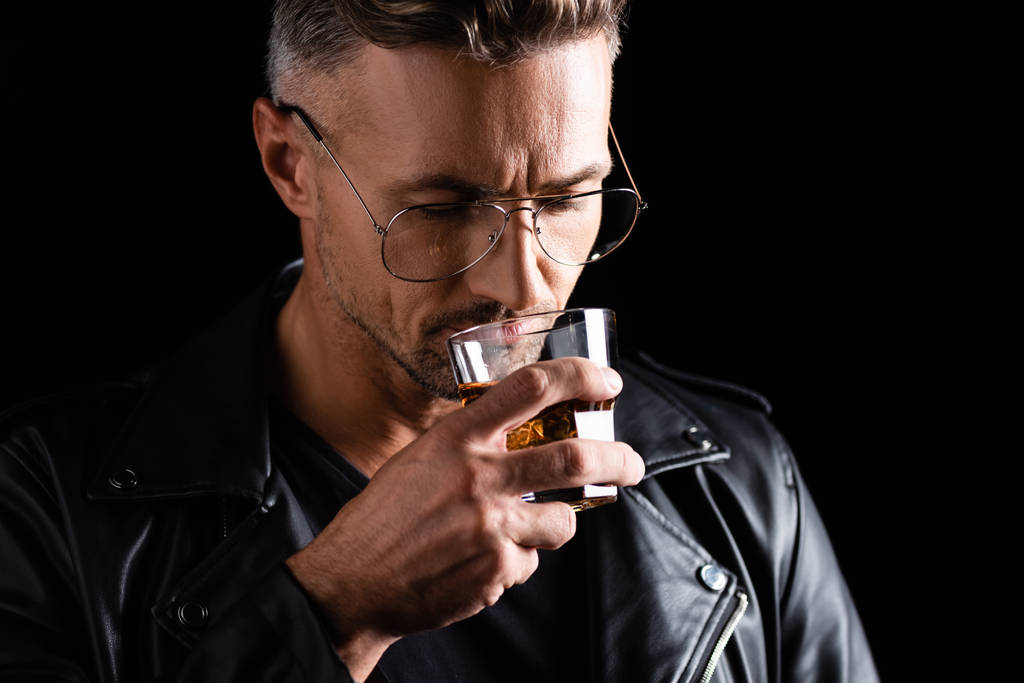Güneş gözlüklü yakışıklı adam, siyah viski içiyor. - Fotoğraf, Görsel
