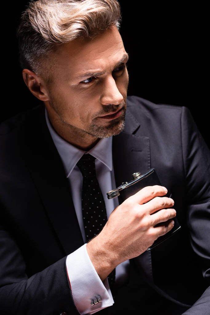 Hombre de negocios guapo sosteniendo frasco aislado en negro
  - Foto, Imagen