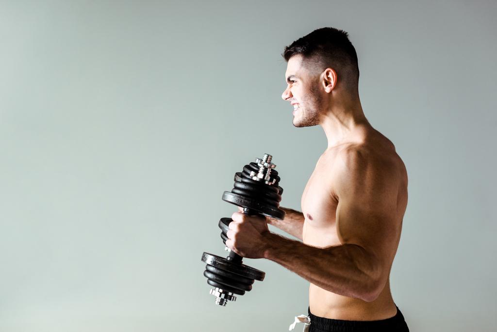 vue latérale de bodybuilder musclé sexy avec torse nu exercice avec haltères isolés sur gris
 - Photo, image
