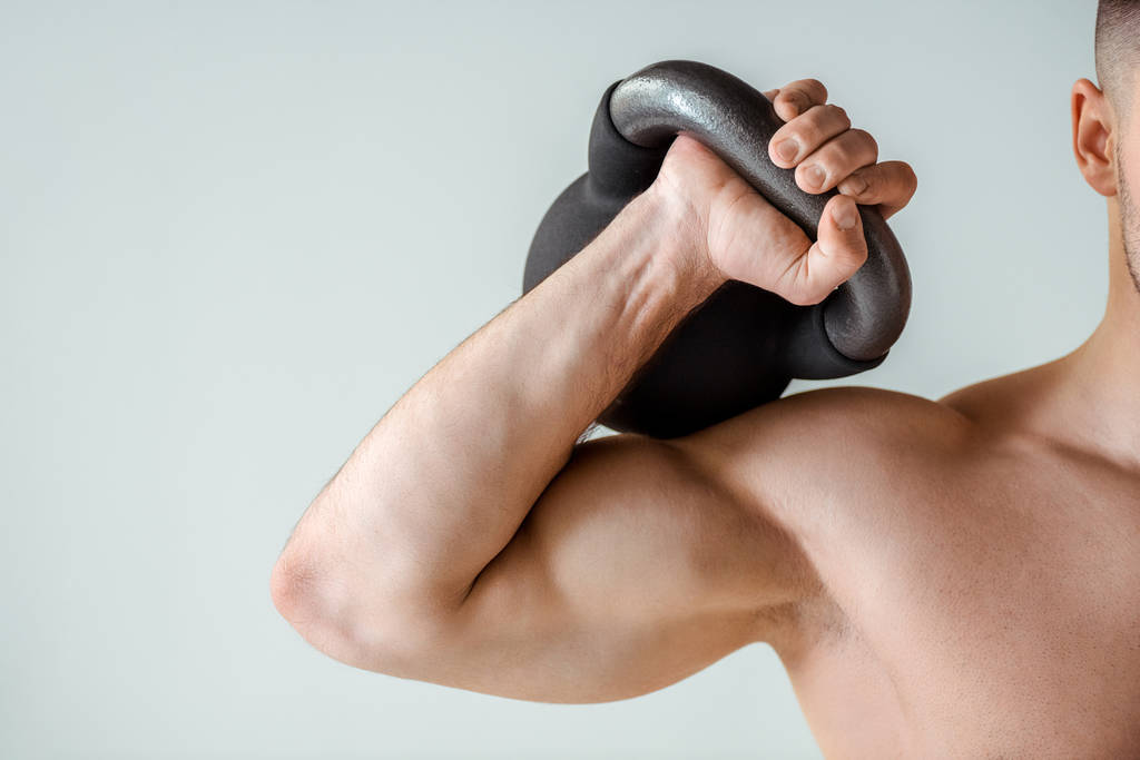 visão parcial do fisiculturista muscular sexy exercício com kettlebell isolado em cinza
 - Foto, Imagem