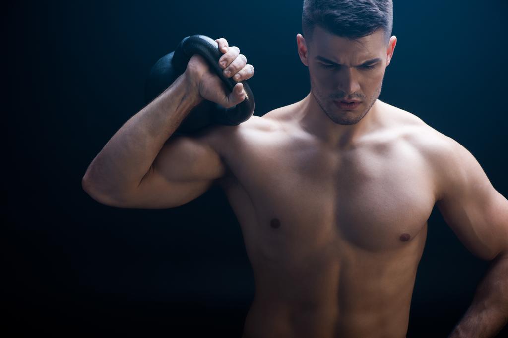 sexy gespierde bodybuilder met kale romp snijden met kettlebell op zwarte achtergrond - Foto, afbeelding