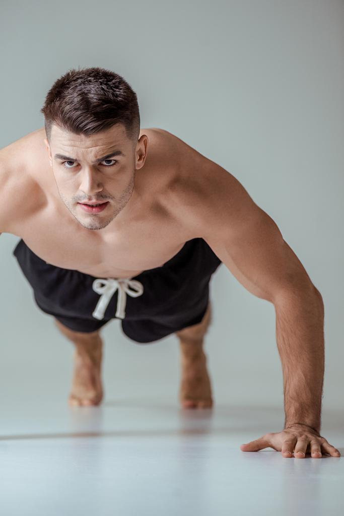 sexy svalnatý sportovec s holým trupem dělá kliky na šedé - Fotografie, Obrázek