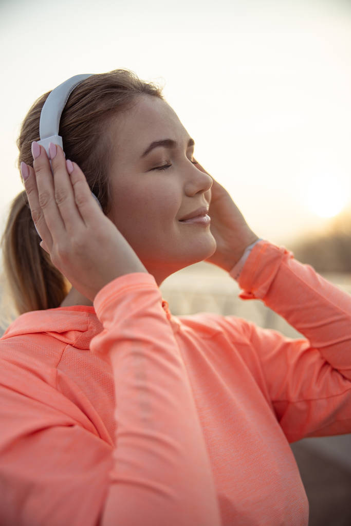 Красива усміхнена жінка слухає музику на відкритому повітрі
 - Фото, зображення