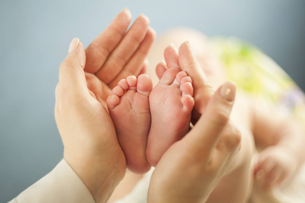 Madre amor Madre sosteniendo los pies de su pequeño bebé, de cerca. Examen de la piel del concepto por un médico
 - Foto, imagen