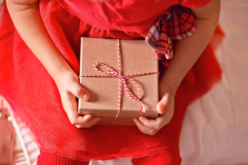 Dítě dívka v červených šatech drží vánoční dárkové krabice v rukou - Fotografie, Obrázek