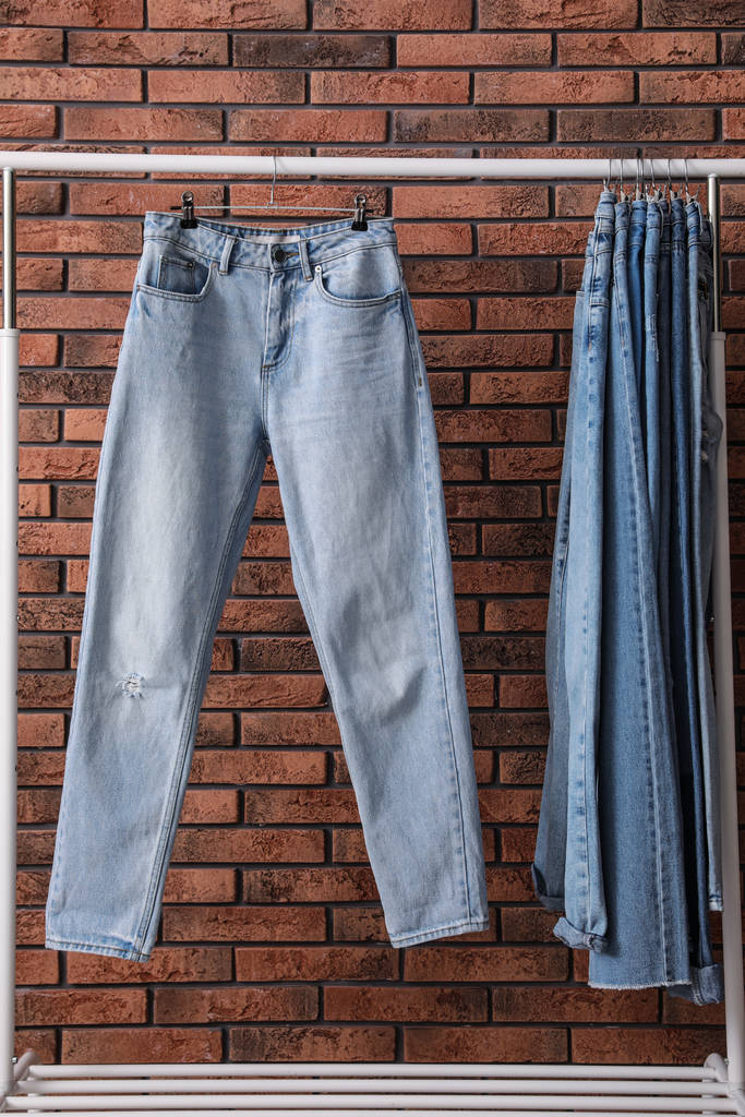 Bastidor con jeans elegantes cerca de la pared de ladrillo
 - Foto, Imagen