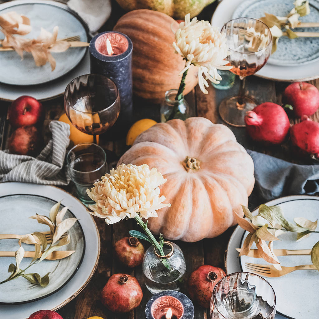 感謝祭の日や家族の集まりの夕食のための秋のテーブル設定。素朴な木製のテーブルの背景に皿、銀器、花や果物の装飾、キャンドルやカボチャ、正方形の作物 - 写真・画像