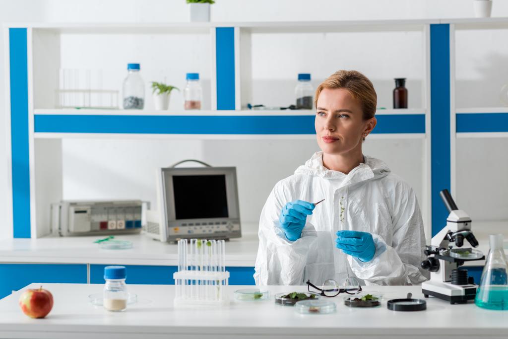 βιολόγος κρατώντας δοκιμαστικό σωλήνα και κοιτάζοντας αλλού στο εργαστήριο   - Φωτογραφία, εικόνα