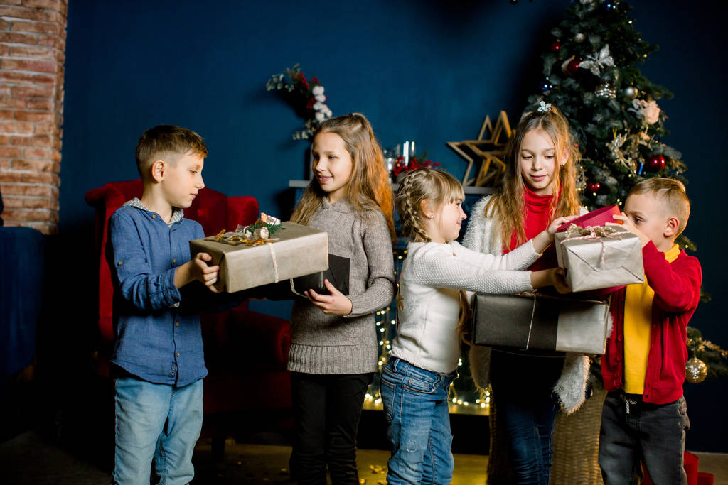 Маленькие красивые дети счастливы получить подарки на Рождество и показать им друг друга
 - Фото, изображение
