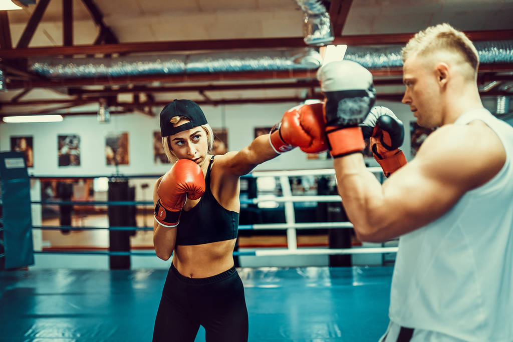 Młoda kobieta ćwiczy z trenerem podczas lekcji boksu i samoobrony - Zdjęcie, obraz