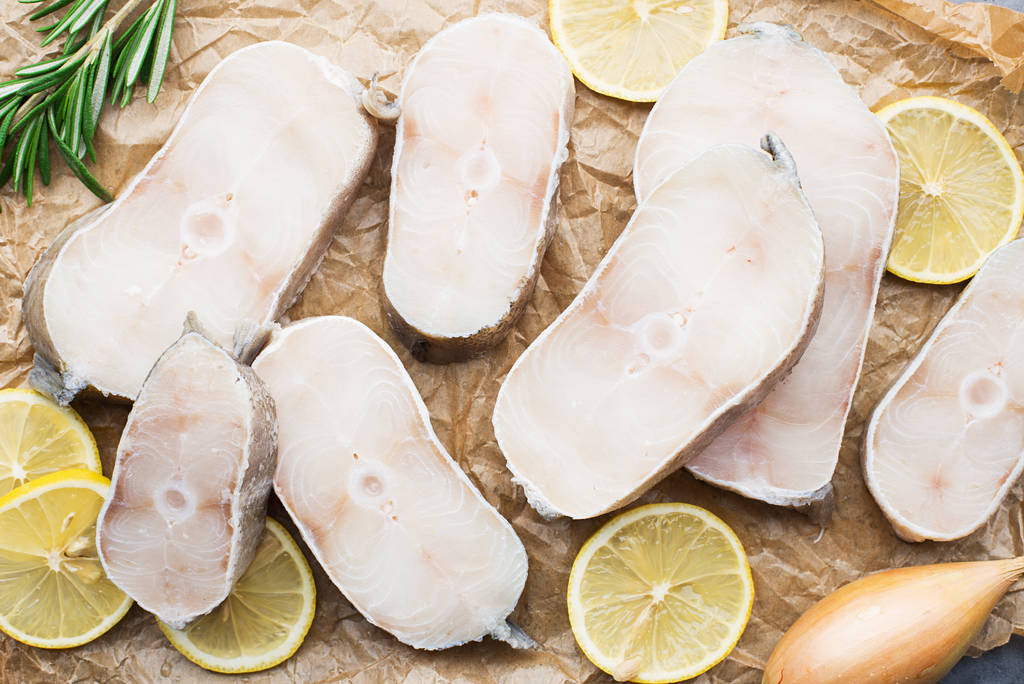 Filetes de bacalao blanco marino orgánico fresco en papel de hornear con limón y romero antes de cocinar. Proteína pura. Alimentación saludable Vista superior
 - Foto, Imagen