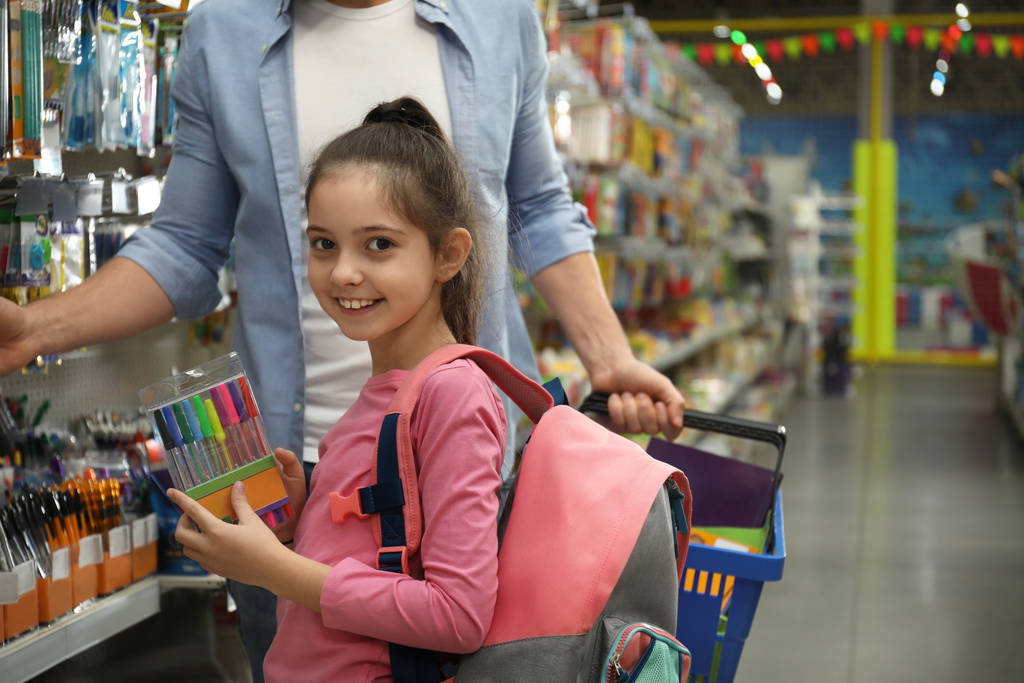Babası olan küçük kız süpermarkette okul kırtasiyesini seçiyor. - Fotoğraf, Görsel