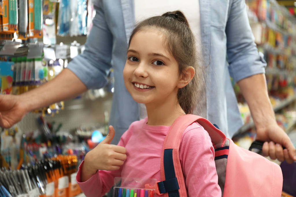 Babası olan küçük kız süpermarkette okul kırtasiyesini seçiyor. - Fotoğraf, Görsel