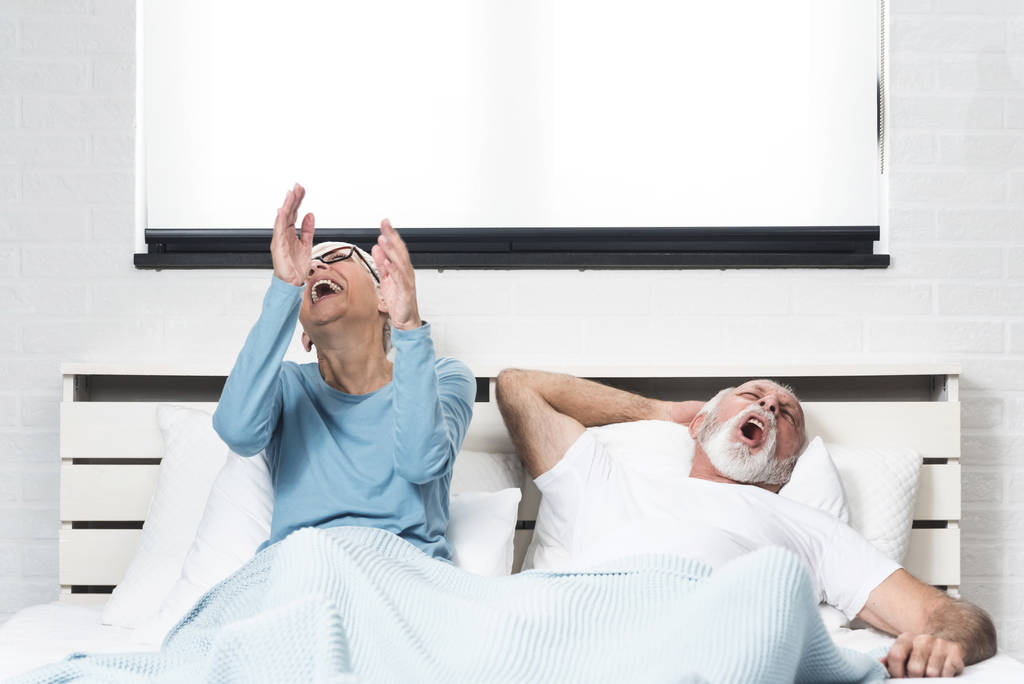 A esposa mais velha não consegue dormir e rir enquanto o marido ressona na cama. Conceito problemas respiratórios
 - Foto, Imagem