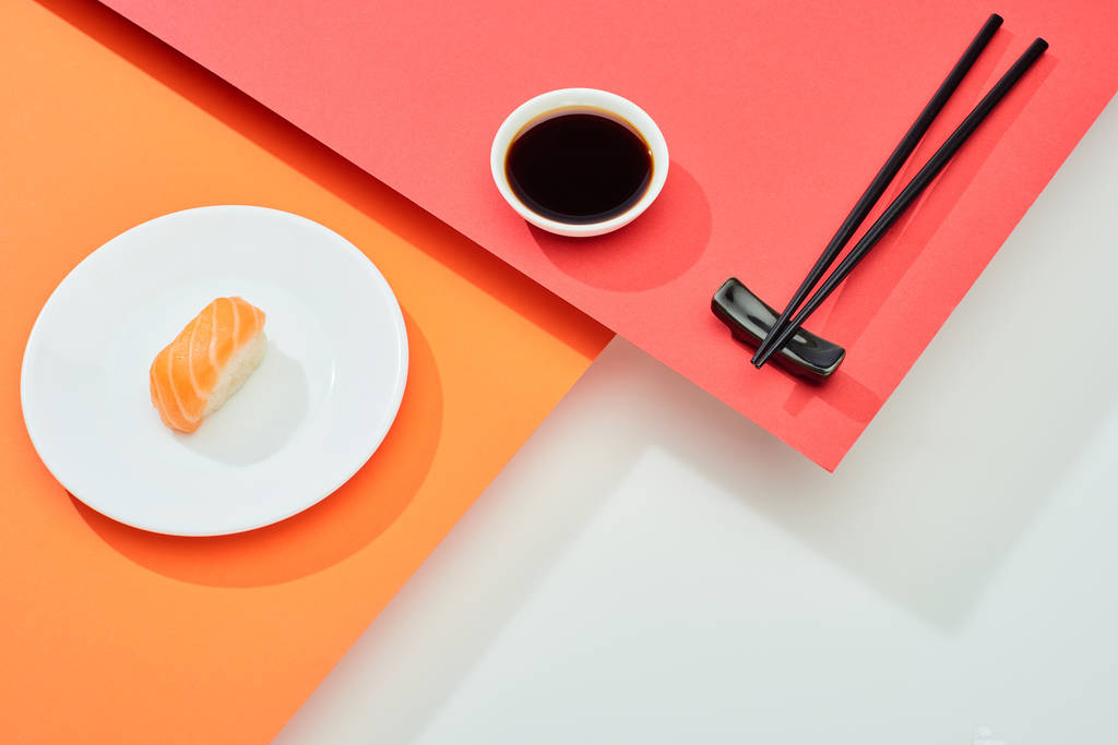 nigiri freschi con salmone vicino alla salsa di soia e bacchette su superficie rossa, arancione, bianca
 - Foto, immagini