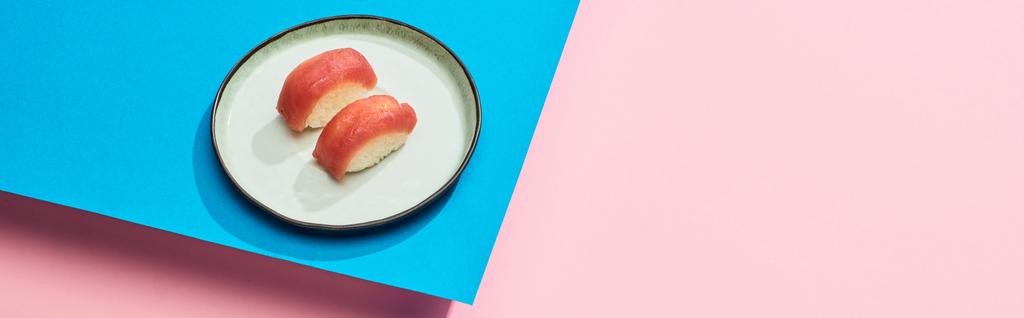 top view of fresh nigiri with tuna on blue, pink background, panoramic shot - 写真・画像