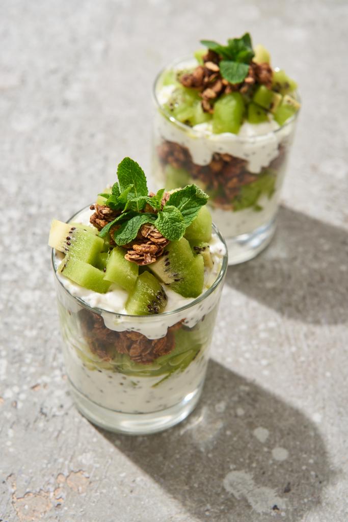 selectieve focus van verse granola met kiwi en yoghurt op grijs betonnen oppervlak - Foto, afbeelding