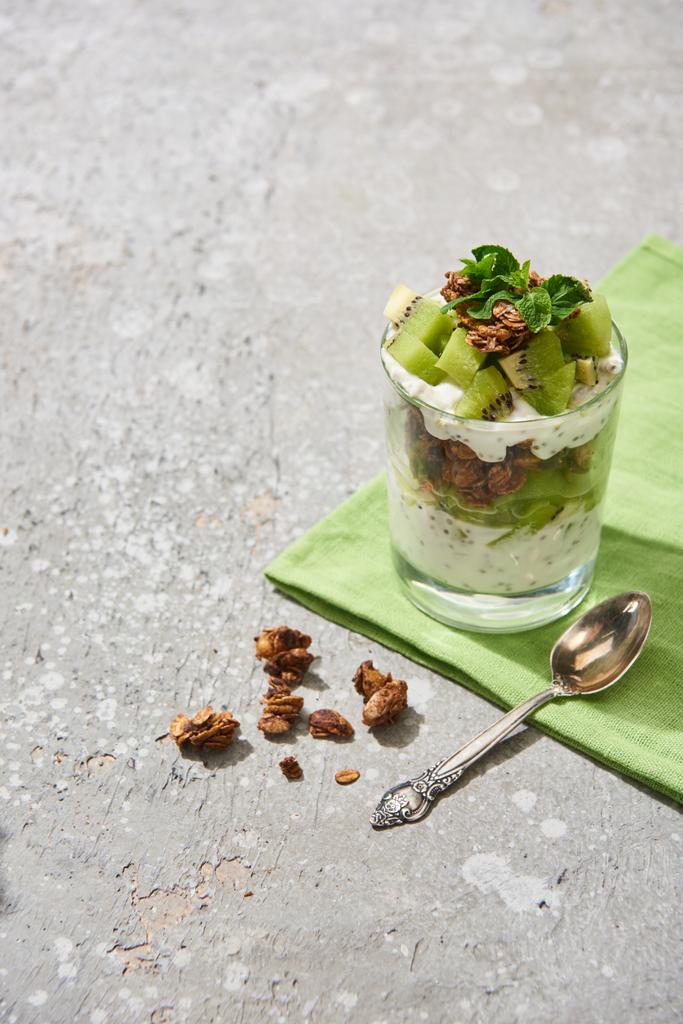 muesli freschi con kiwi e yogurt su una superficie di cemento grigio con tovagliolo e cucchiaio
 - Foto, immagini