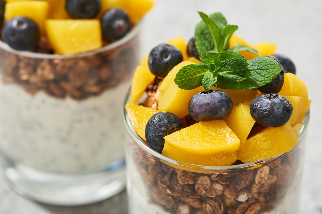close up view of tasty granola with canned peach, blueberries and mint - Photo, Image