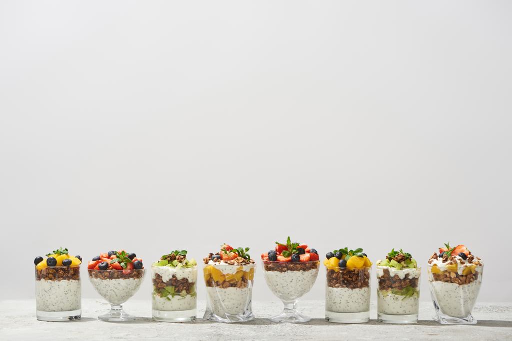 νόστιμη γκρανόλα σε ποτήρια με φρούτα και μούρα που απομονώνονται σε λευκό - Φωτογραφία, εικόνα