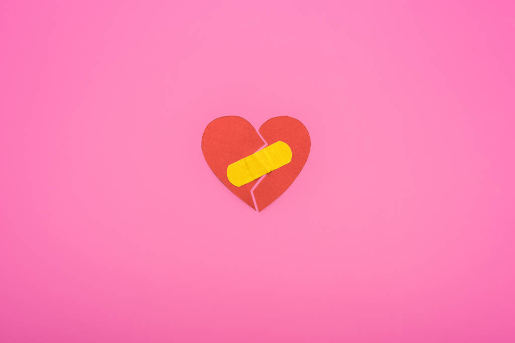 Draufsicht auf gebrochenes Papier Herz mit Patch auf rosa Hintergrund vereinzelt verbunden - Foto, Bild