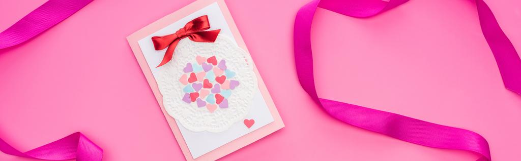 ピンクに孤立したリボン付きのバレンタイングリーティングカードのトップビュー、パノラマショット - 写真・画像