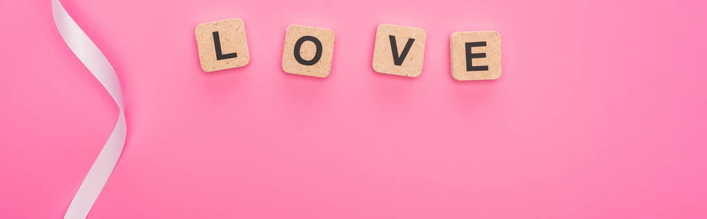πάνω όψη της κυρτής κορδέλας και ξύλινα μπλοκ με γράμματα αγάπης που απομονώνονται σε ροζ, πανοραμική λήψη - Φωτογραφία, εικόνα